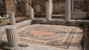 At the edge of a floor mosaic with a circular pattern inside a square, there are depictions of riders on the backs of dolphins